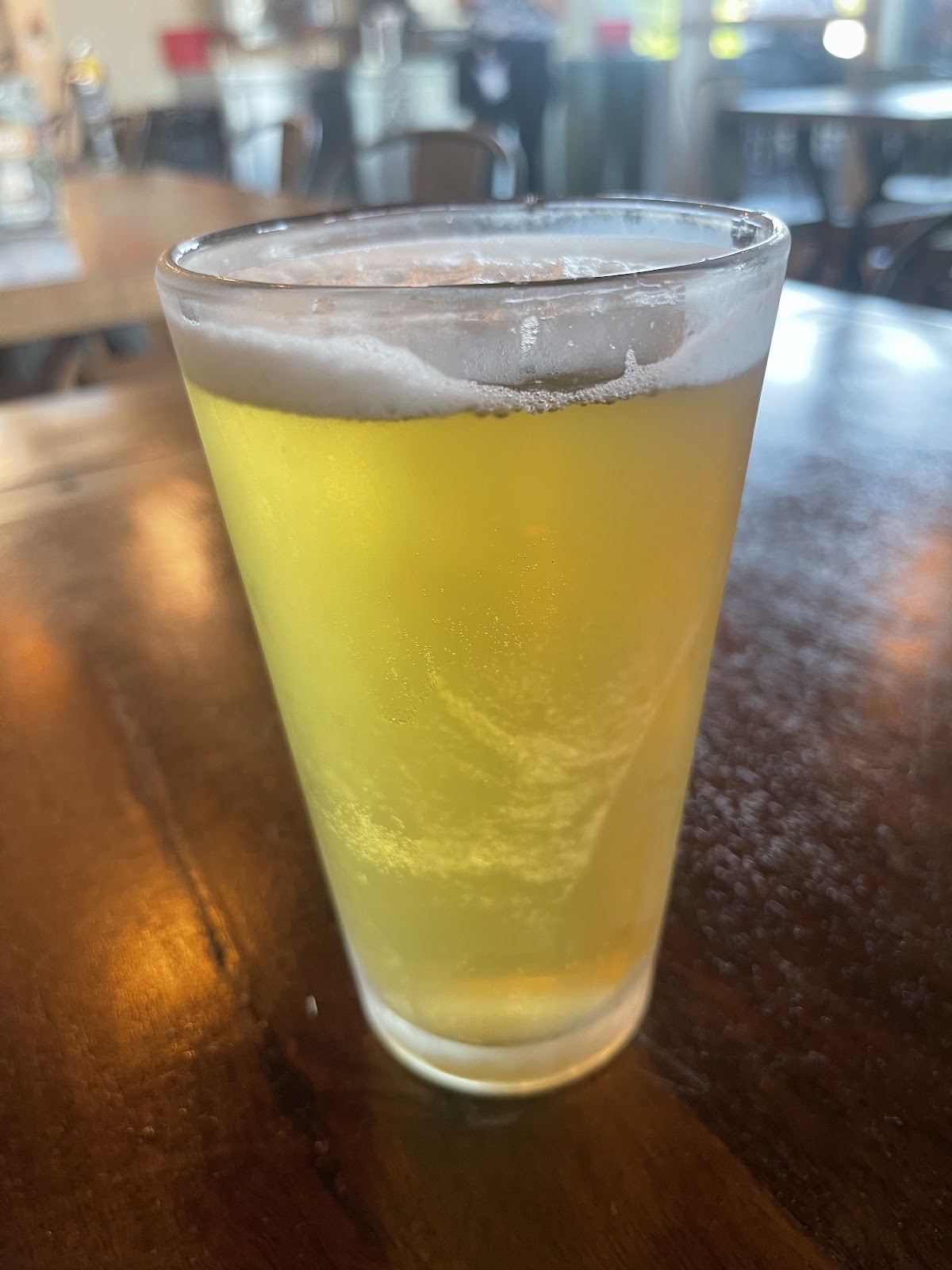 A golden draft beer on a wood table at Bushfire Kitchen during happy hour