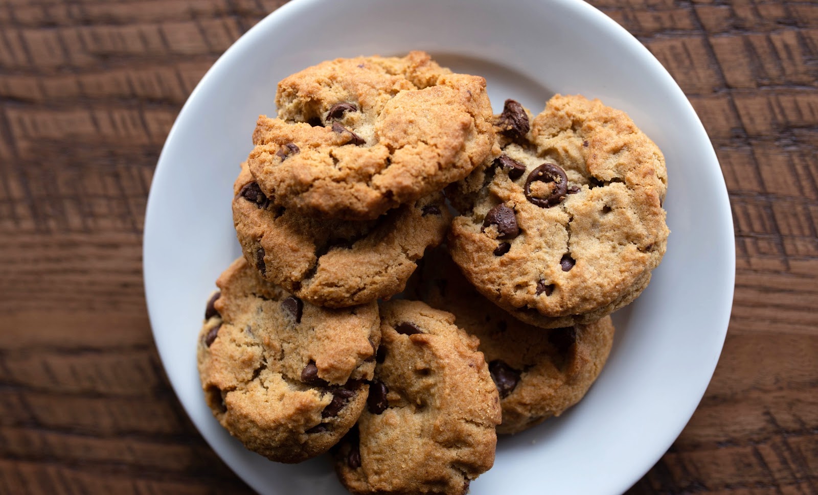 Fresh-baked chocolate chip cookies on a white plate on a wood table at Bushfire Kitchen
