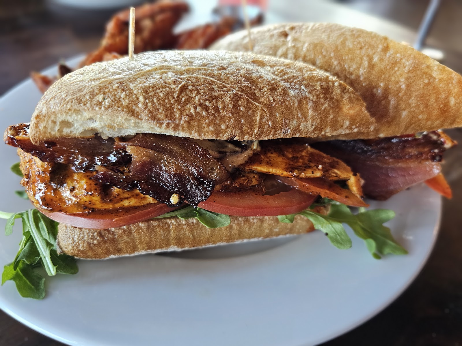 A grilled chicken sandwich with bacon, arugula and tomato on a toasted ciabatta roll at Bushfire Kitchen