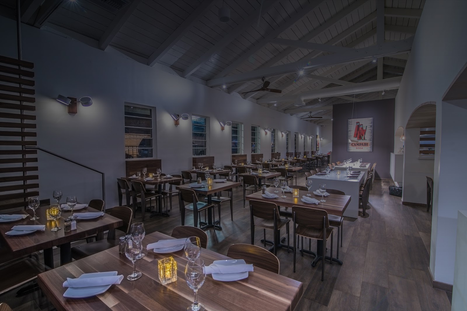 The dining room at Ciao Pasta, white-beamed vaulted ceiling over walnut tables set for dinner