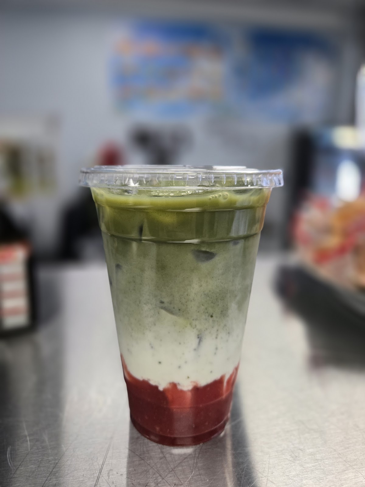An iced strawberry matcha latte showing a green matcha layer over milk and a red strawberry layer at the bottom