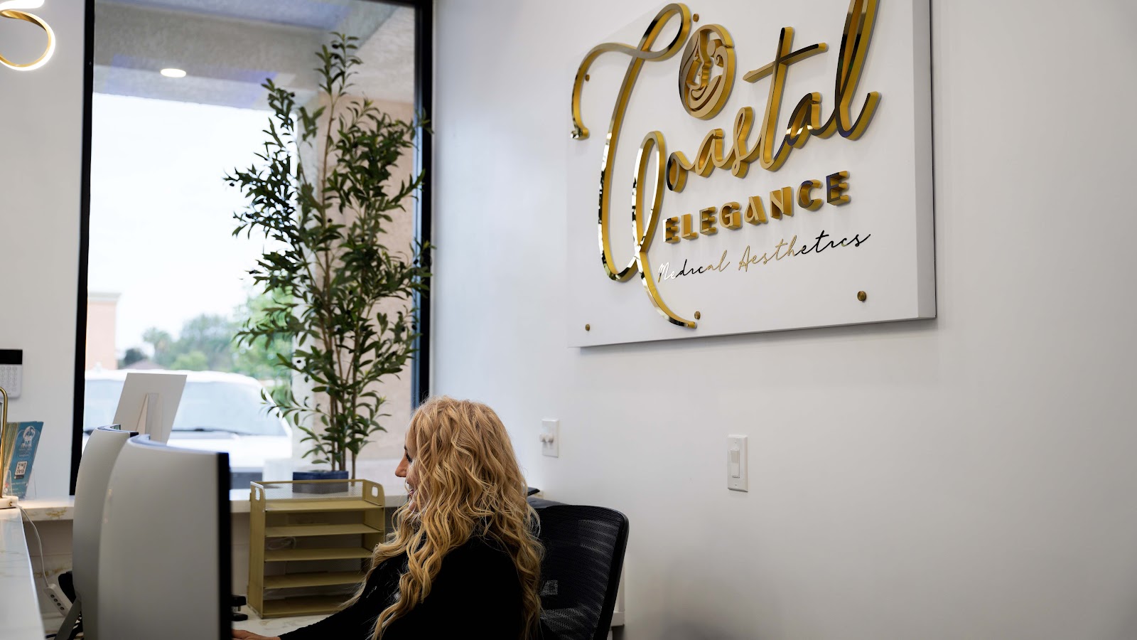 The welcoming reception desk and gold wordmark inside Coastal Elegance
