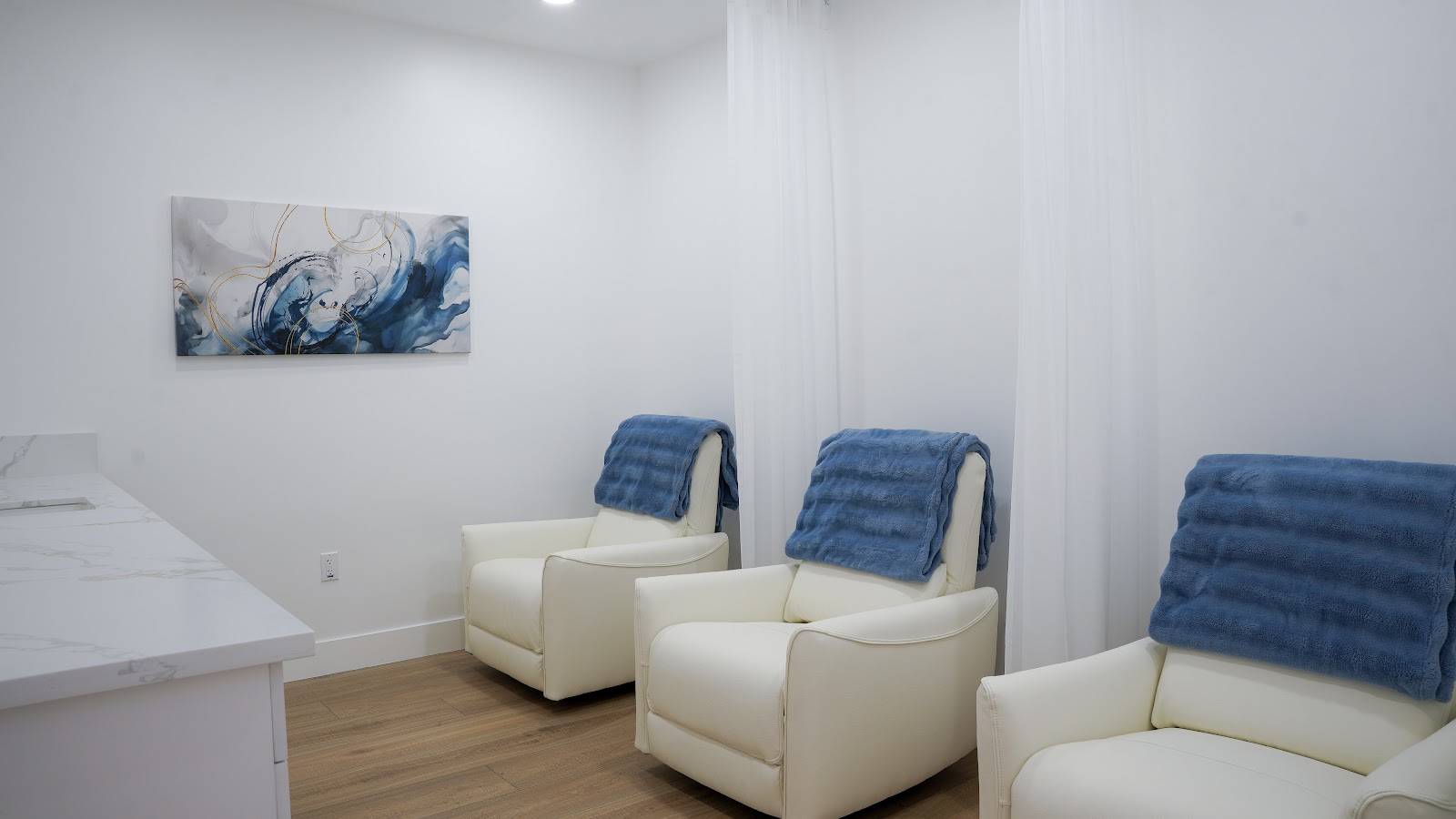 A calm, light-filled recovery lounge with coastal wave art