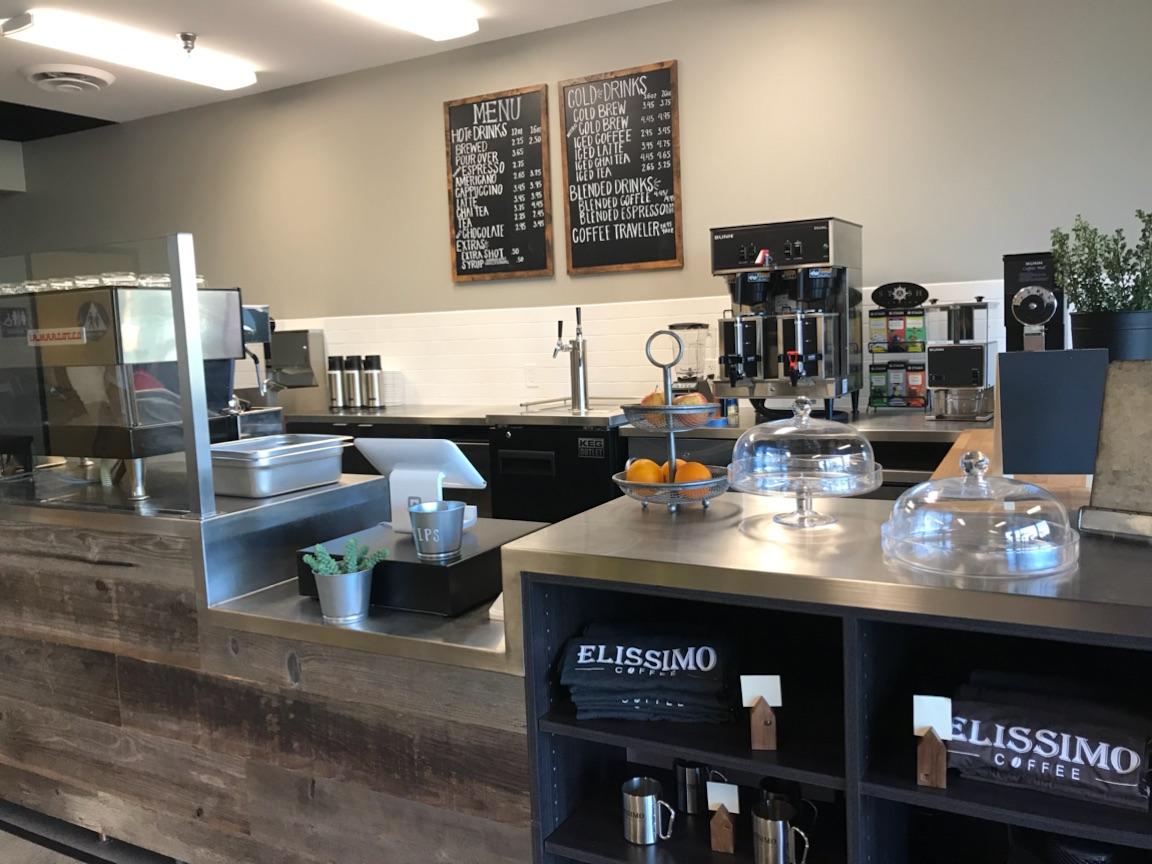 The Elissimo Coffee bar in Rancho Santa Margarita: chalkboard menu, brewing equipment, ELISSIMO COFFEE merch on a reclaimed-wood counter