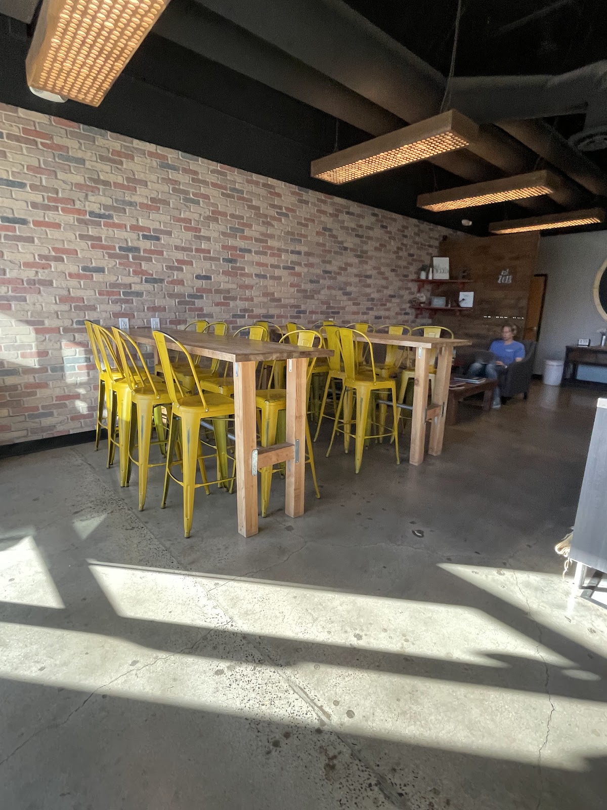 Reclaimed-brick wall, yellow industrial chairs, communal table at Elissimo Coffee