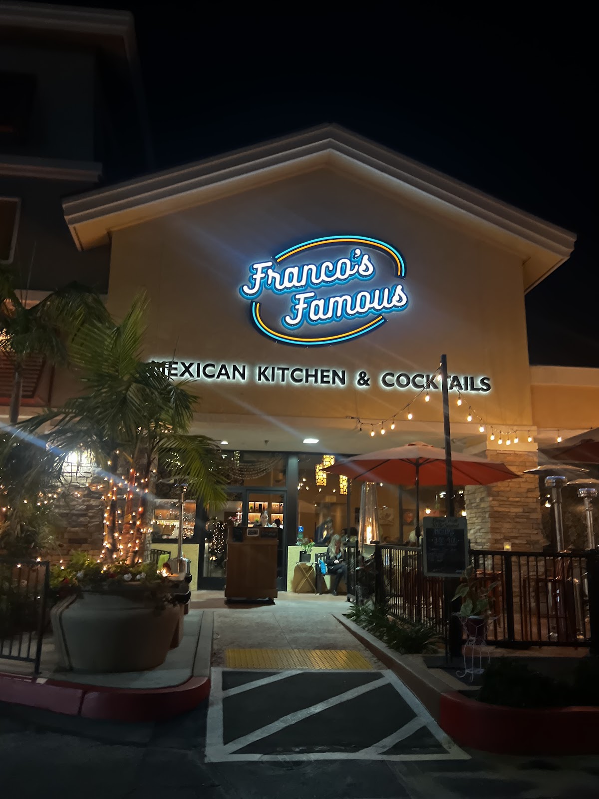 Franco's Famous storefront glowing with its blue neon sign at night