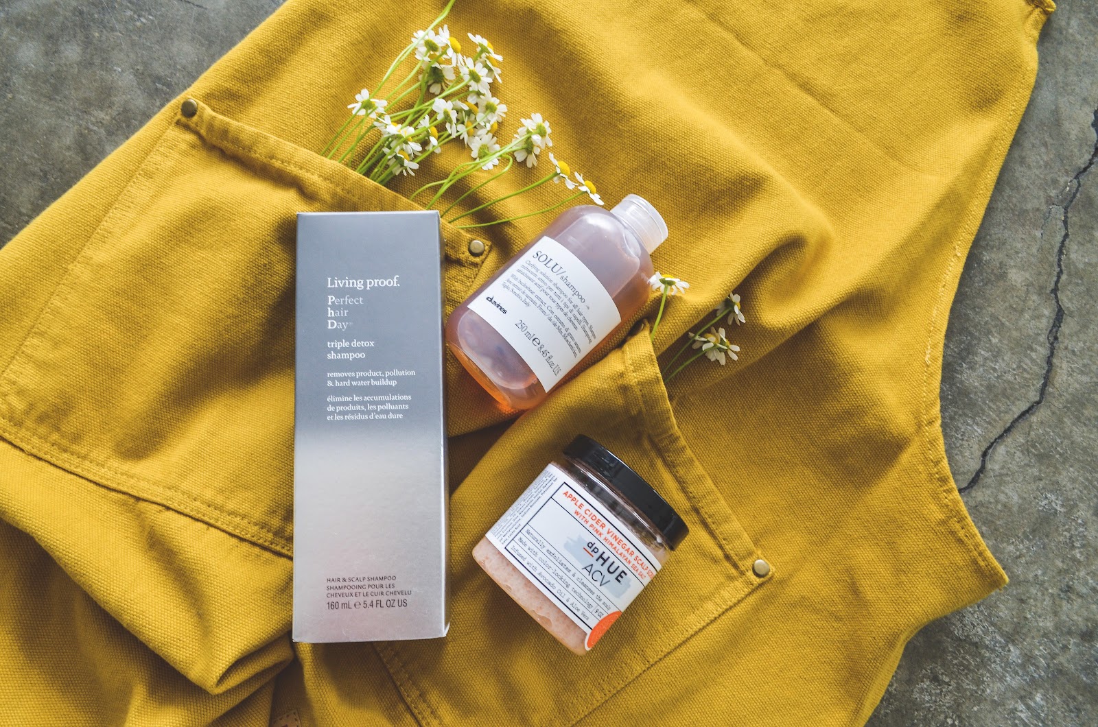 Hair-care products laid on a golden apron with chamomile flowers at Gold & Braid