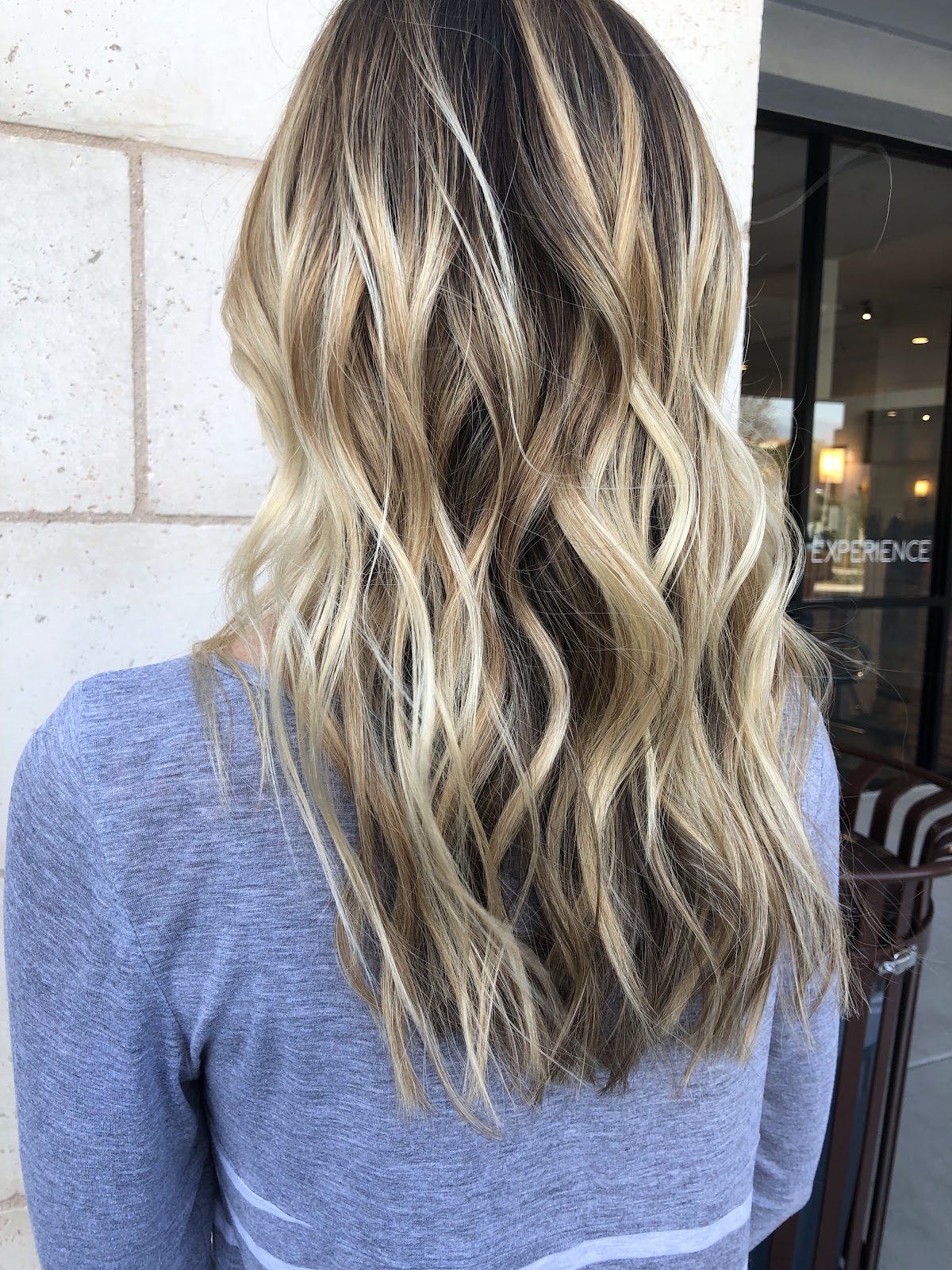 Long, dimensional blonde balayage with soft waves, styled at Gold & Braid