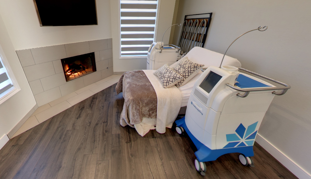 A body-contouring device beside a draped bed in a Gravity treatment room