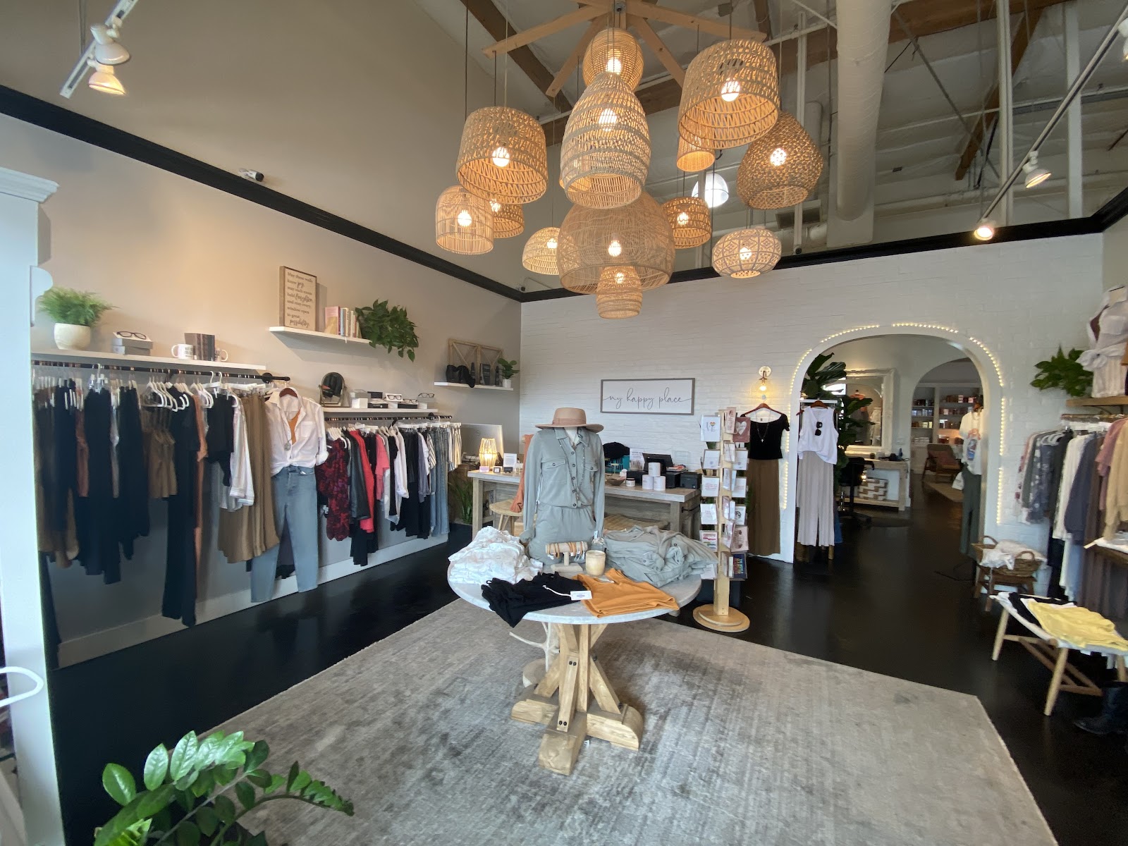 The boutique inside H Studio: clothing racks, a cluster of woven rattan pendant lights, and a center display table