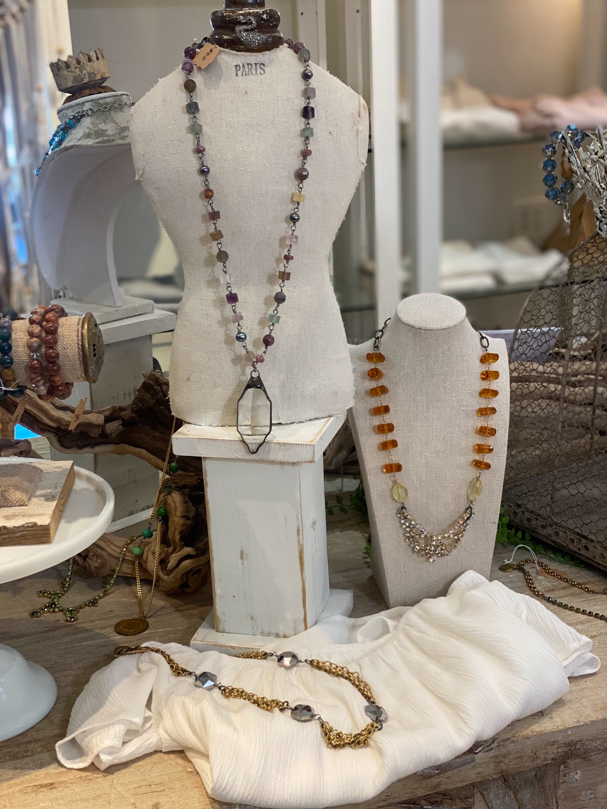 Handmade beaded and stone jewelry displayed on linen dress forms in the H Studio boutique