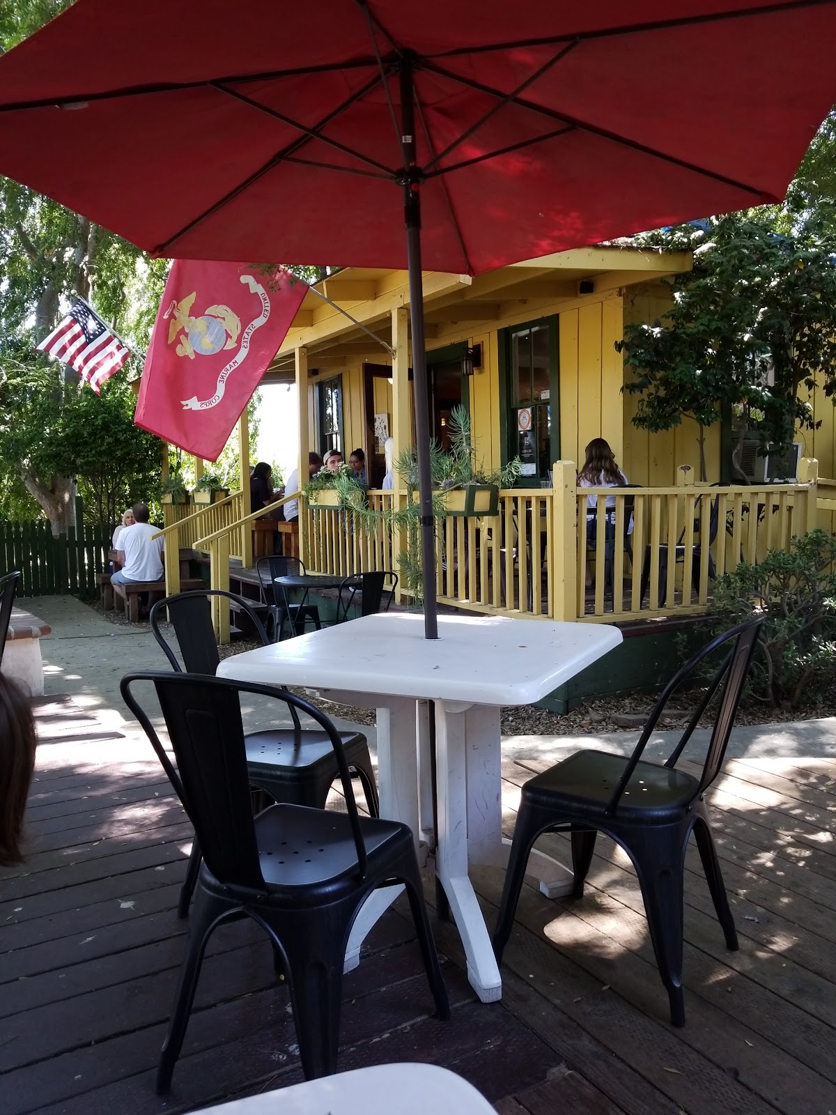 The porch of Hidden House Coffee with the American flag and the Marine Corps standard flying above the picnic tables