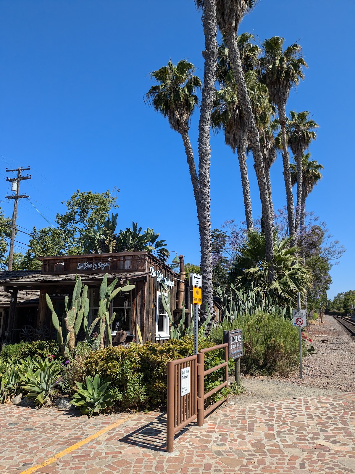 The Hidden House Coffee cottage seen from Los Rios Street with palms above and the Amtrak track to the right