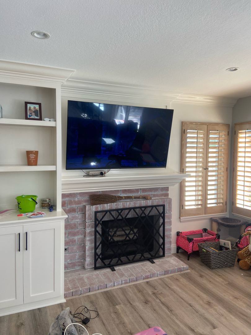 TV over a brick fireplace, beside built-ins