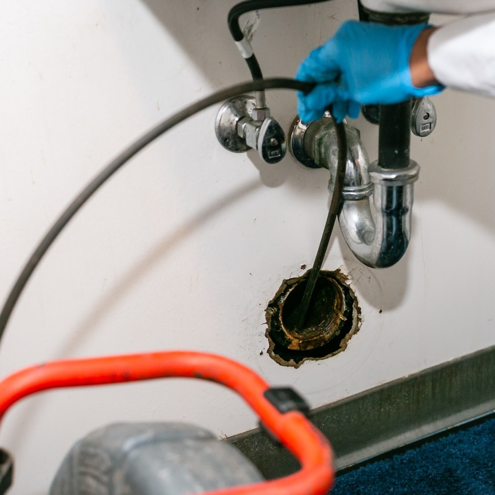 Kalka technician clearing a sink drain line with a drain auger