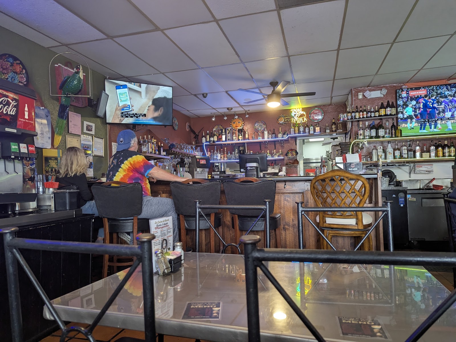 The bar at La Cocina de Ricardo with tequila bottles, neon and a soccer match on the TV
