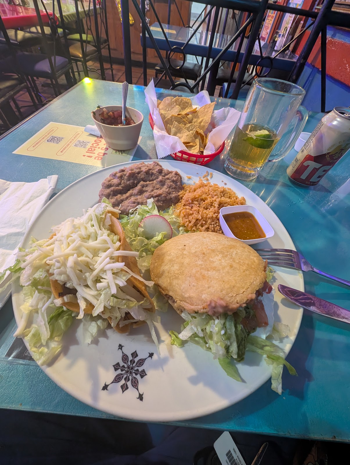 A combination plate at La Cocina de Ricardo with crispy tacos topped with shredded cheese and lettuce, a sope, Mexican rice, refried beans and salsa