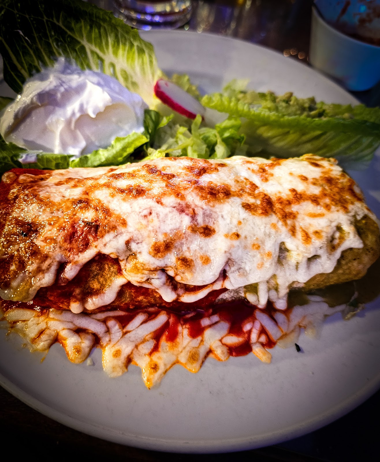 Enchiladas suizas at La Cocina de Ricardo: enchiladas smothered in red sauce and melted cheese, browned on top, with romaine lettuce, sour cream and a radish
