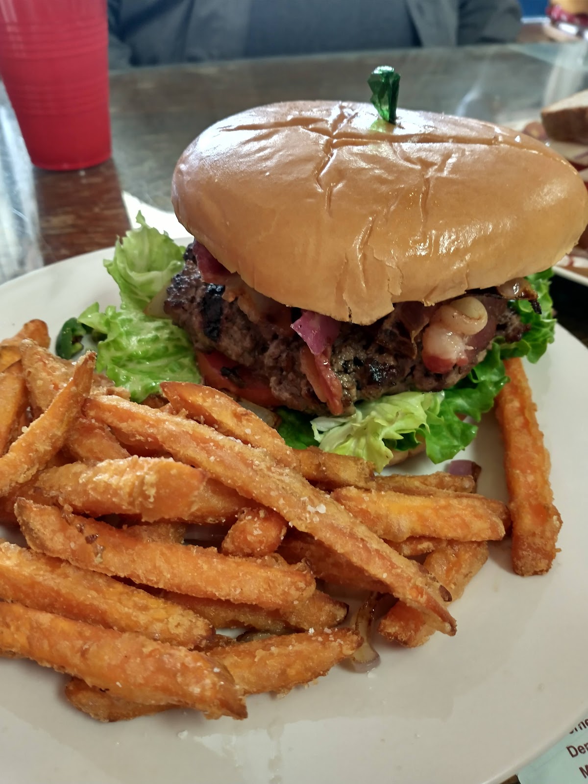 A bacon cheeseburger with a stack of sweet potato fries