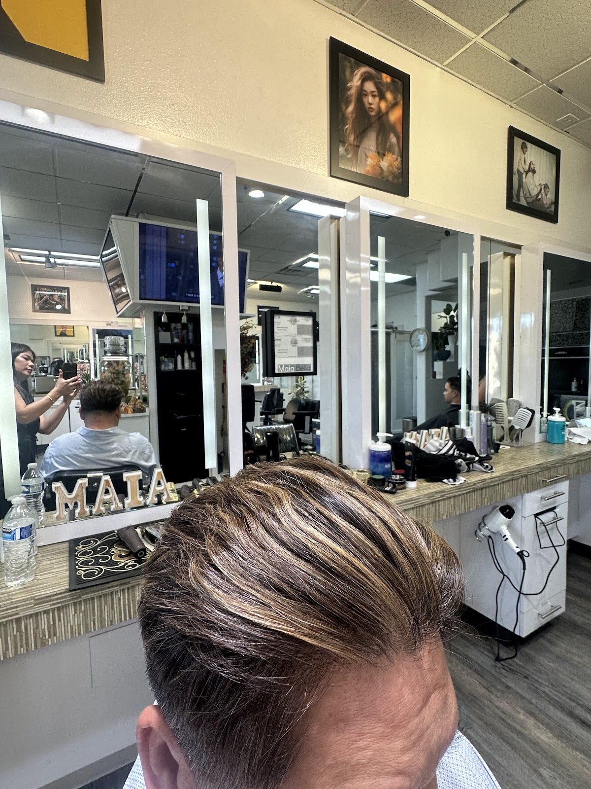A styled top with blonde highlights at the mirror at Maia Bella, with Maia name letters on the counter