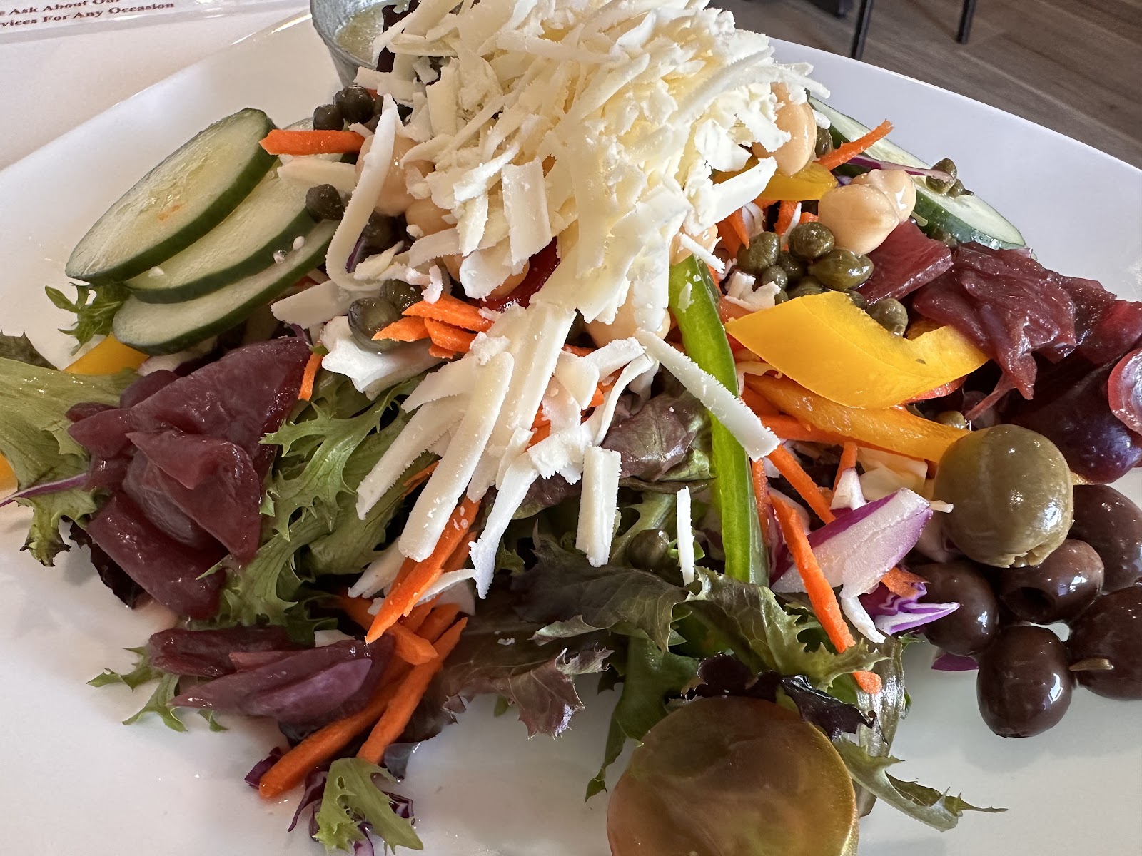 Mediterranean Salad at Mangi Con Amore. Mixed greens, cucumber, peppers, kalamata olives, capers, bresaola, with shaved ricotta salata on top. Big plate, lunch-sized.