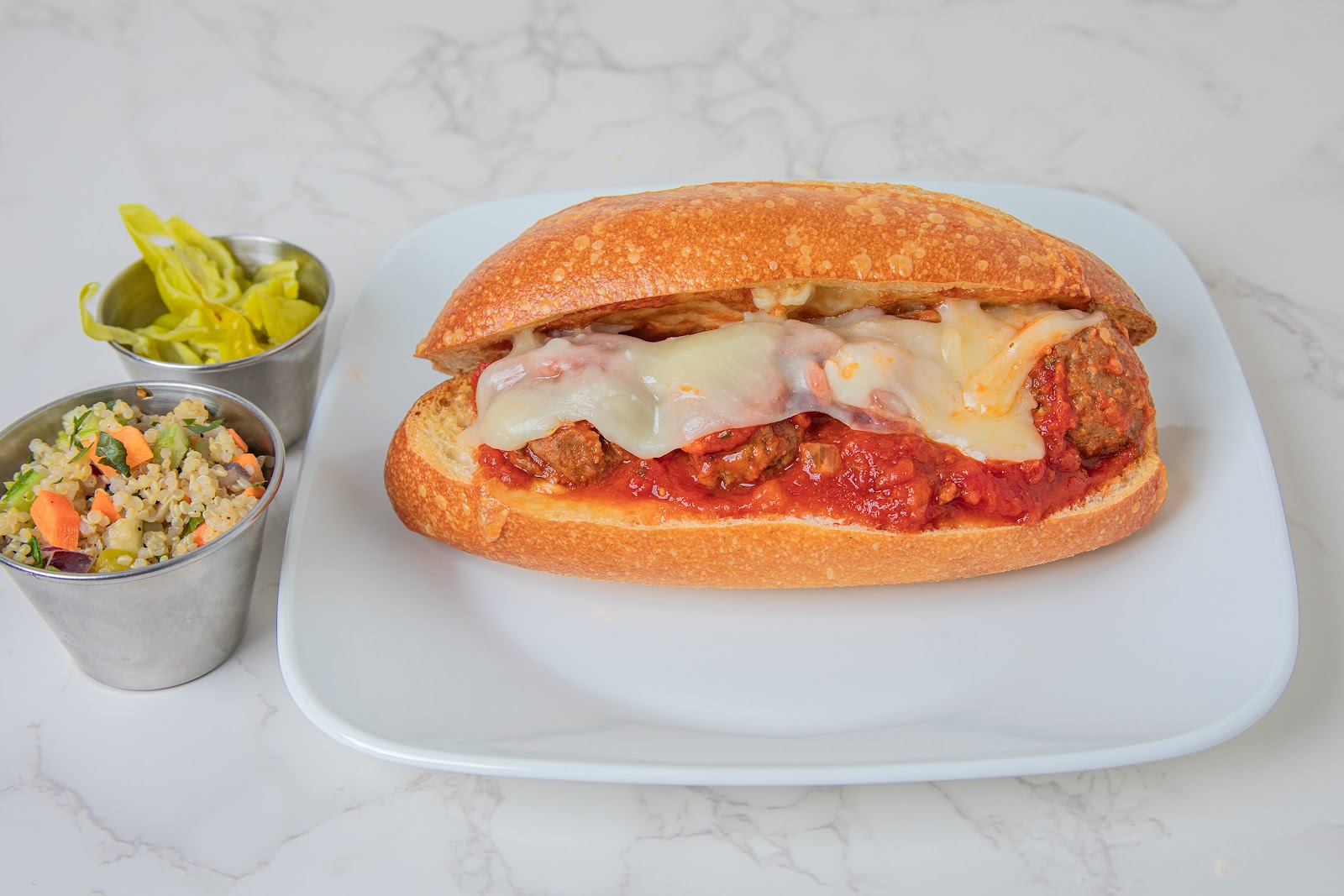 The meatball Parmigiano panini at Mangi Con Amore, melted mozzarella over house meatballs in marinara, served with a side cup of quinoa and pepperoncini