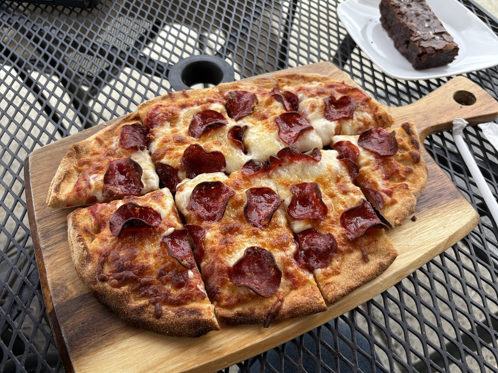 Pepperoni & Cheese Pizza at Mangi Con Amore. Wood-board service, charred edges. One review writes "each bite was even better than the last, the cheese, the dough, the presentation — all perfect."