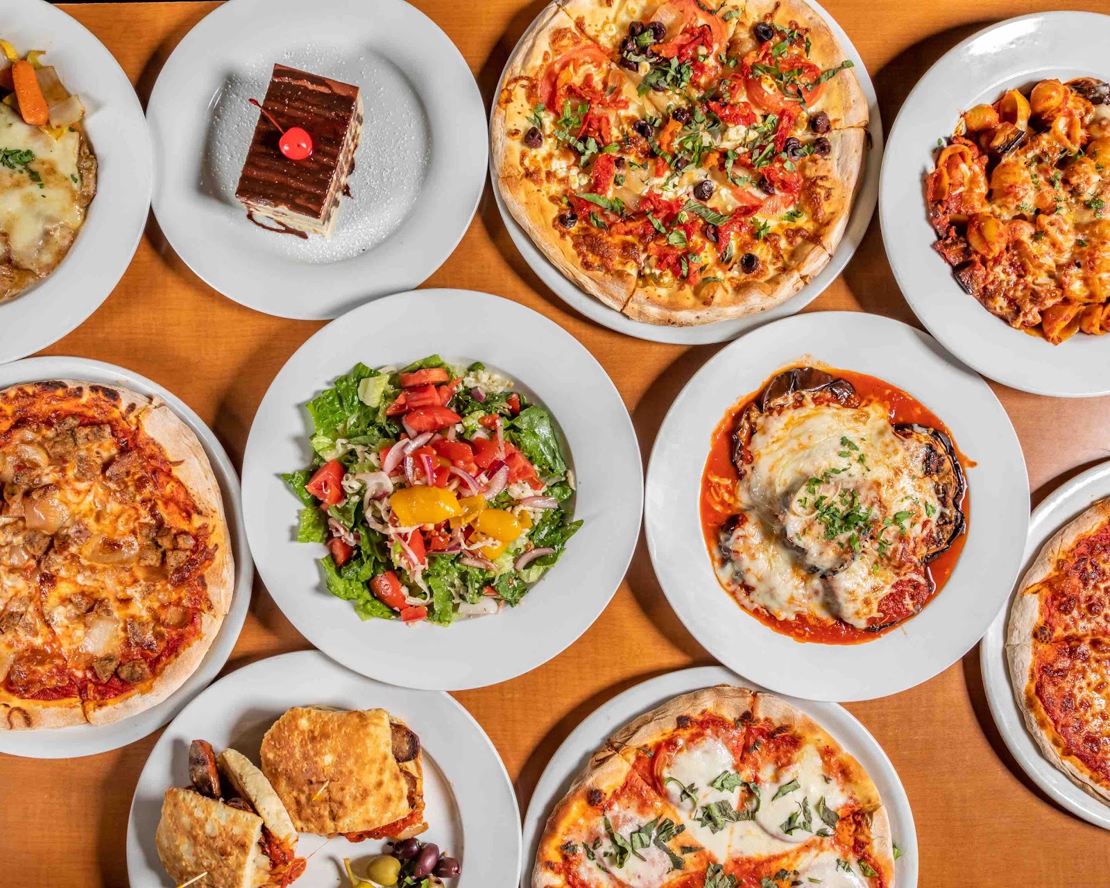 A family-style spread of pizzas, pastas, and salads at Mangia Bene