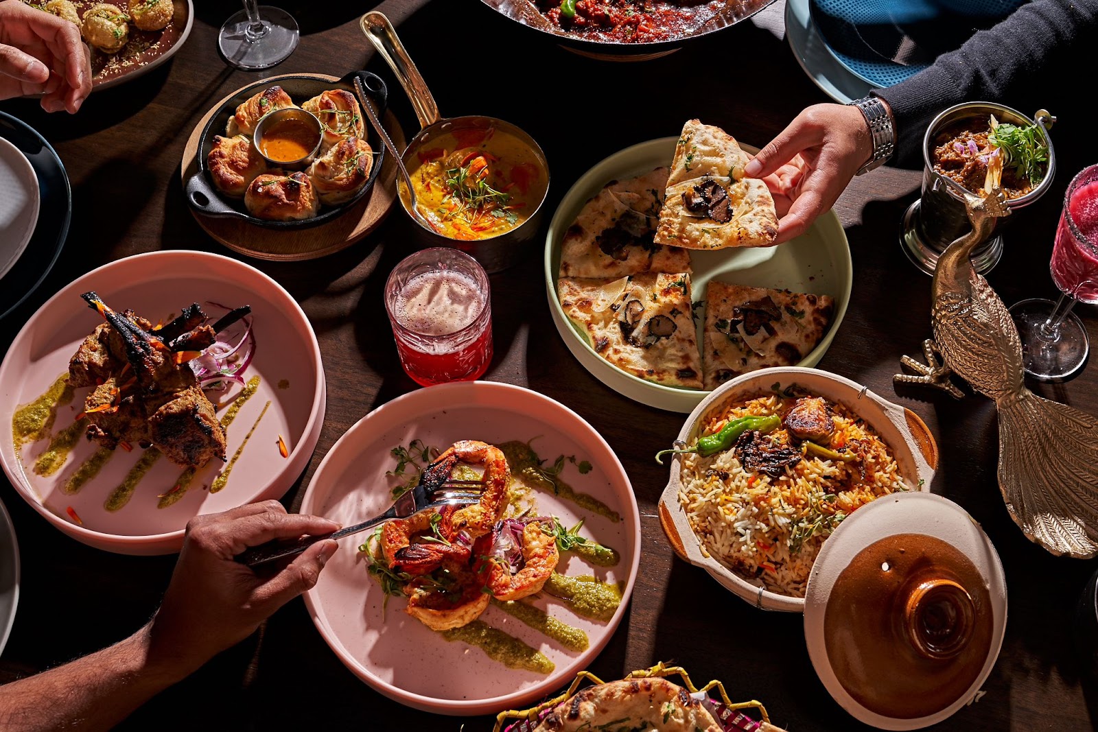 A spread of food at Mint Desi Craft Kitchen, several plates arranged with curry, biryani, naan and chutneys