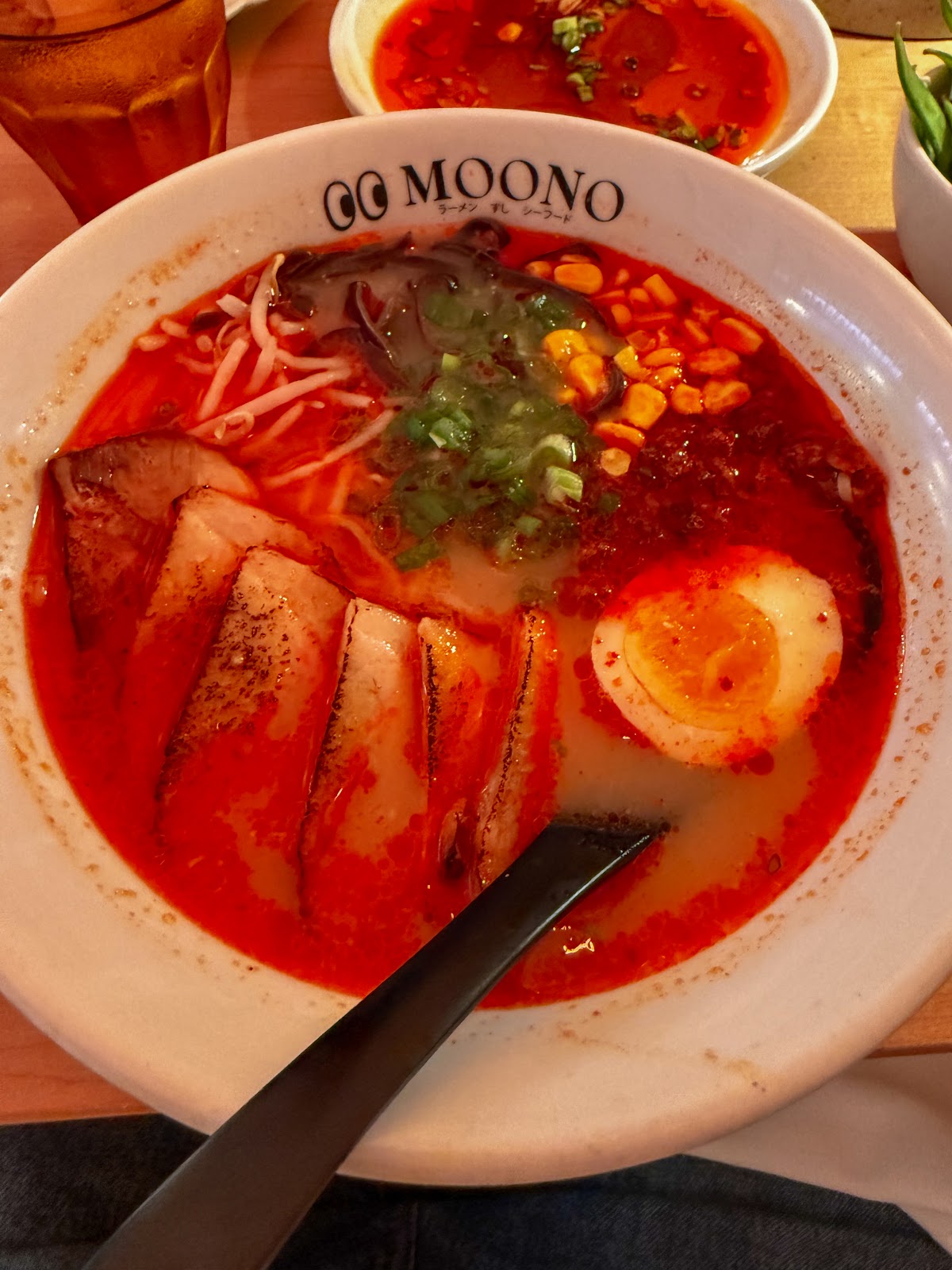 Spicy Pork Ramen at MOONO. Secret chili paste, tonkotsu broth, torched chashu, ground pork, corn, mushroom, soft egg. The red bowl in the photos.