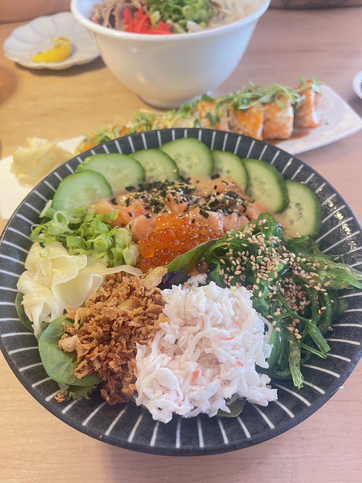 Poke Bowl at MOONO. Three scoops of protein over rice and salad. Salmon, ikura, cucumber, seaweed salad, crab, crispy onion, sesame, white ginger. Secret sauce.