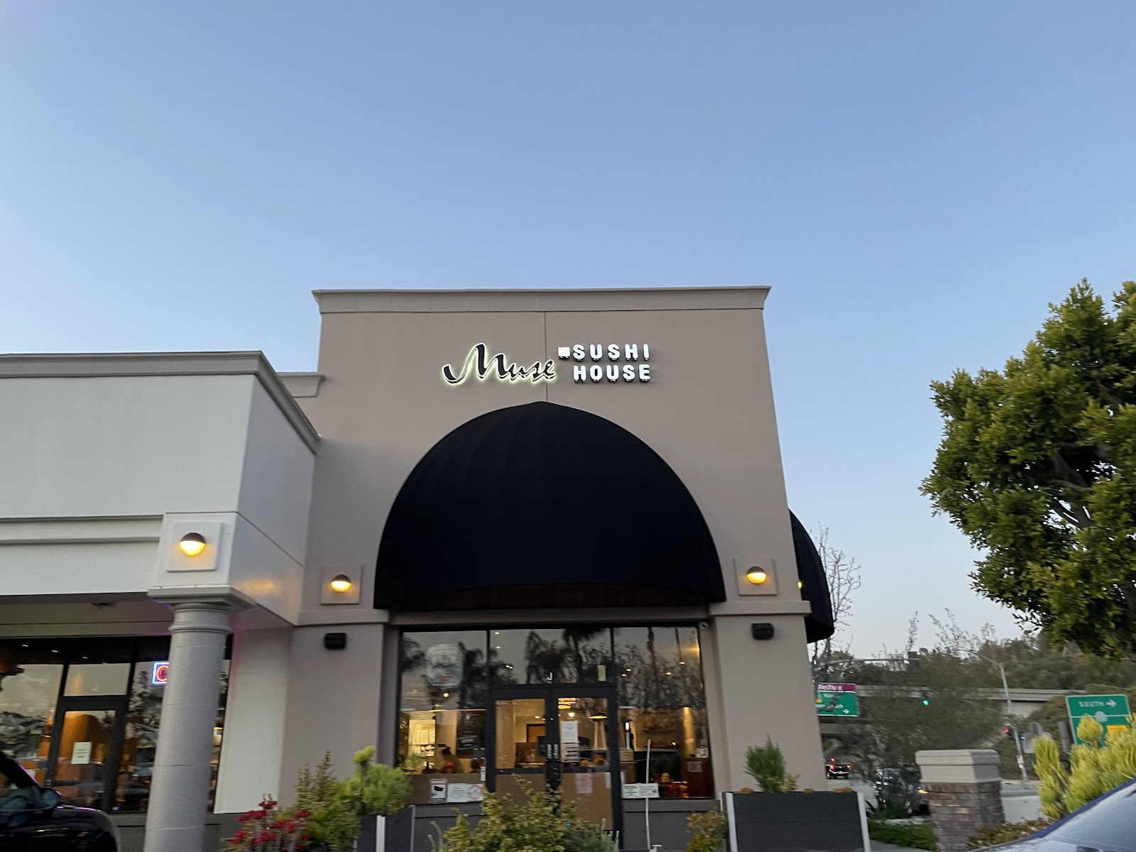 The Muse Sushi House storefront in Laguna Niguel, black dome awning and lit signage at dusk