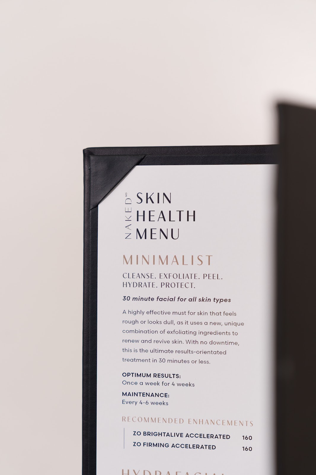 The NakedMD Skin Health Menu folio, open to the Minimalist 30 minute facial