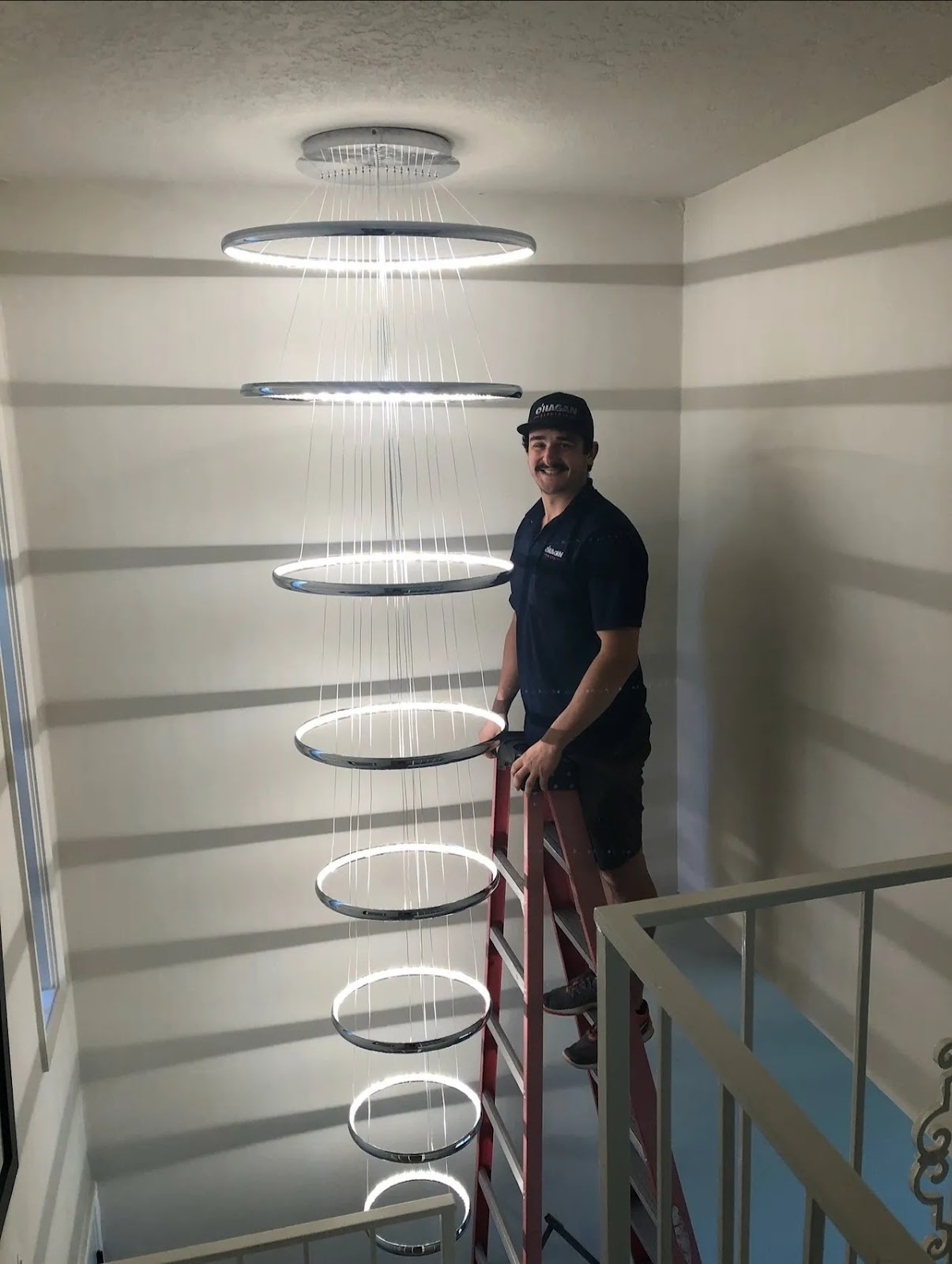 Stacked LED ring chandelier installed by O'Hagan Electric in a two-story stairwell