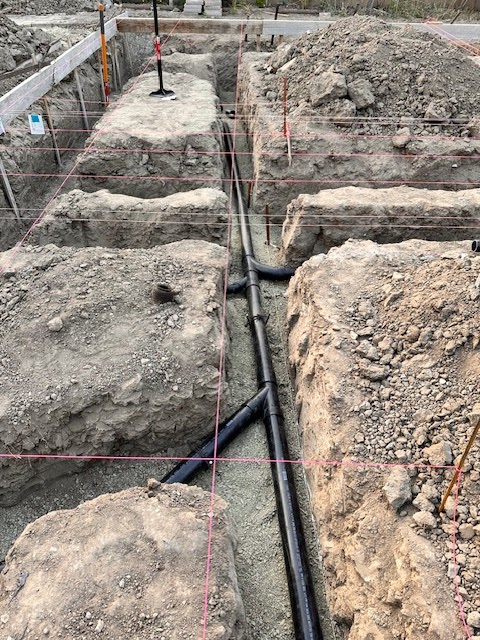 Patriot Plumbing clearing a yard drain at the cleanout with hoses on a stone patio