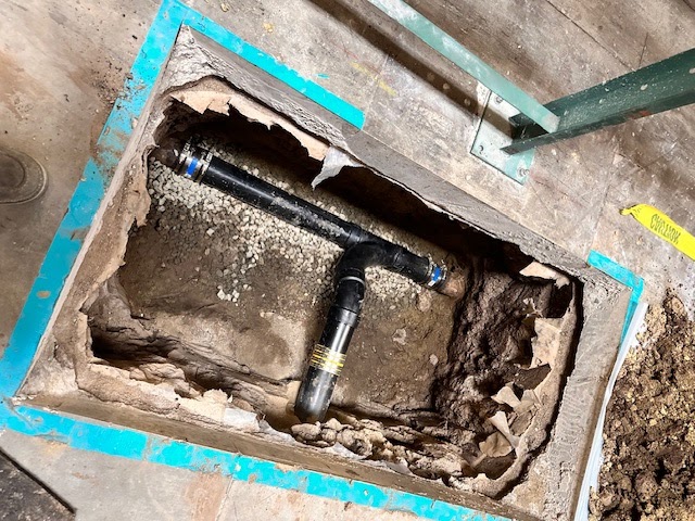 New ABS pipe T-fitting set into an opened floor slab by Patriot Plumbing