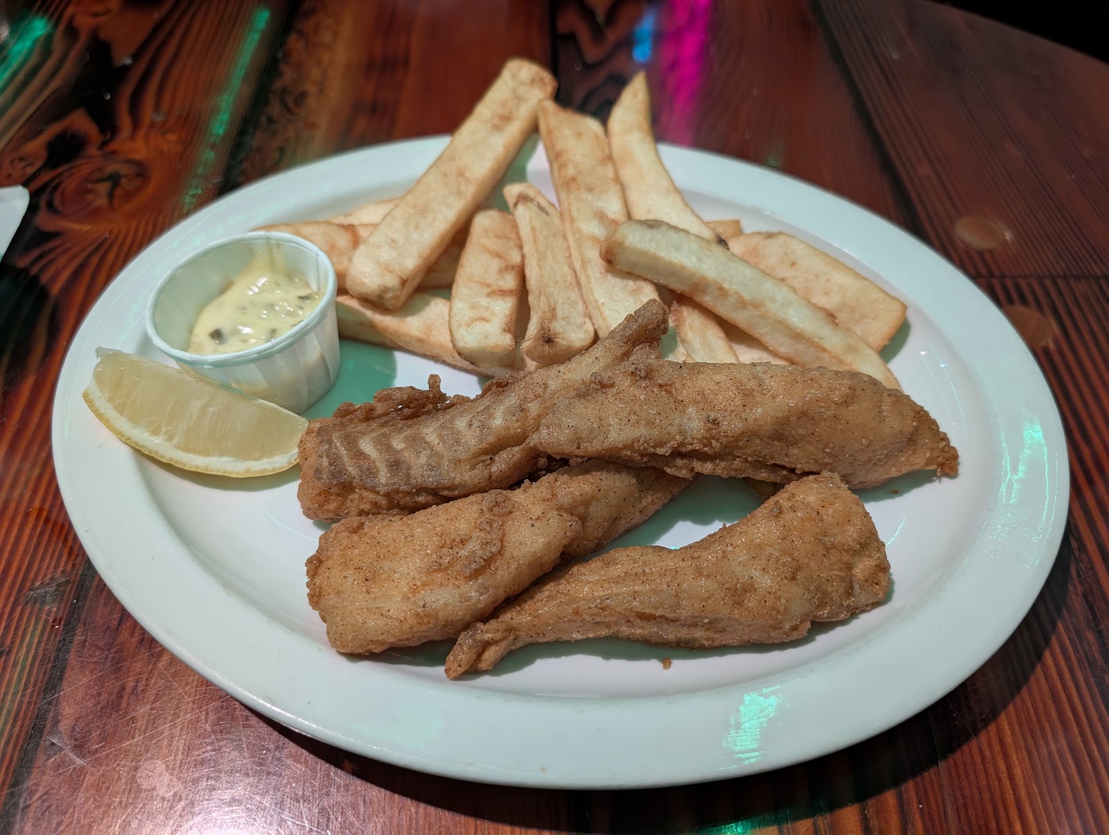 Beer-battered fish and chips with lemon and tartar sauce on a white plate