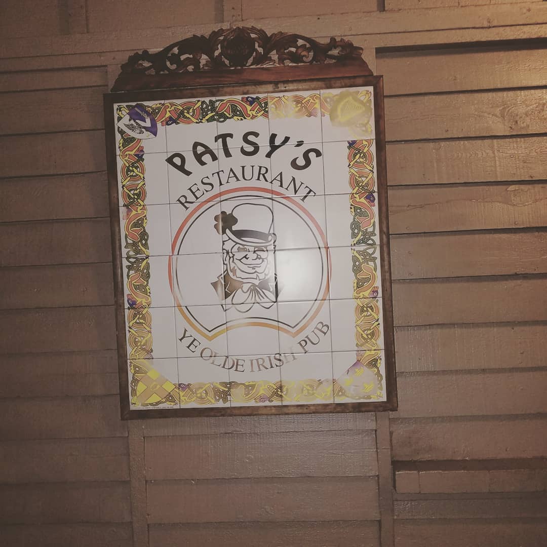 The front door of Patsy's under a green awning, the window decal reading Where Ireland Comes To You, neon OPEN sign lit