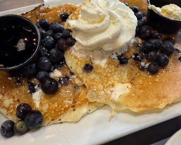 A platter of blueberry ricotta 'n cream pancakes at Plumeria Cafe, blanketed in wild blueberries and whipped cream