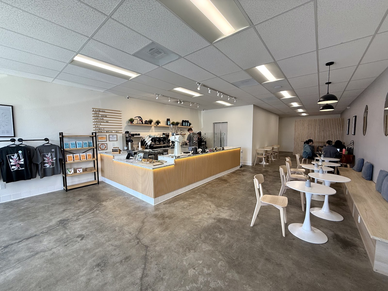 The Redshift dining room with white tulip chairs, a wood-slat accent wall, bench seating and the menu board behind the marble counter