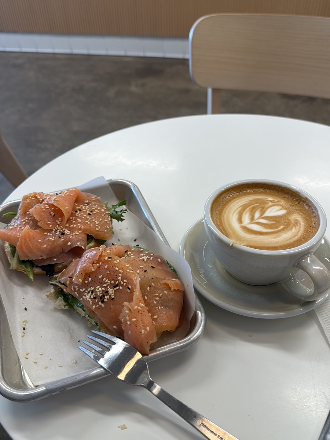 Smoked salmon toast at Redshift, open-face with greens and sesame on a steel tray beside a cortado in a grey cup