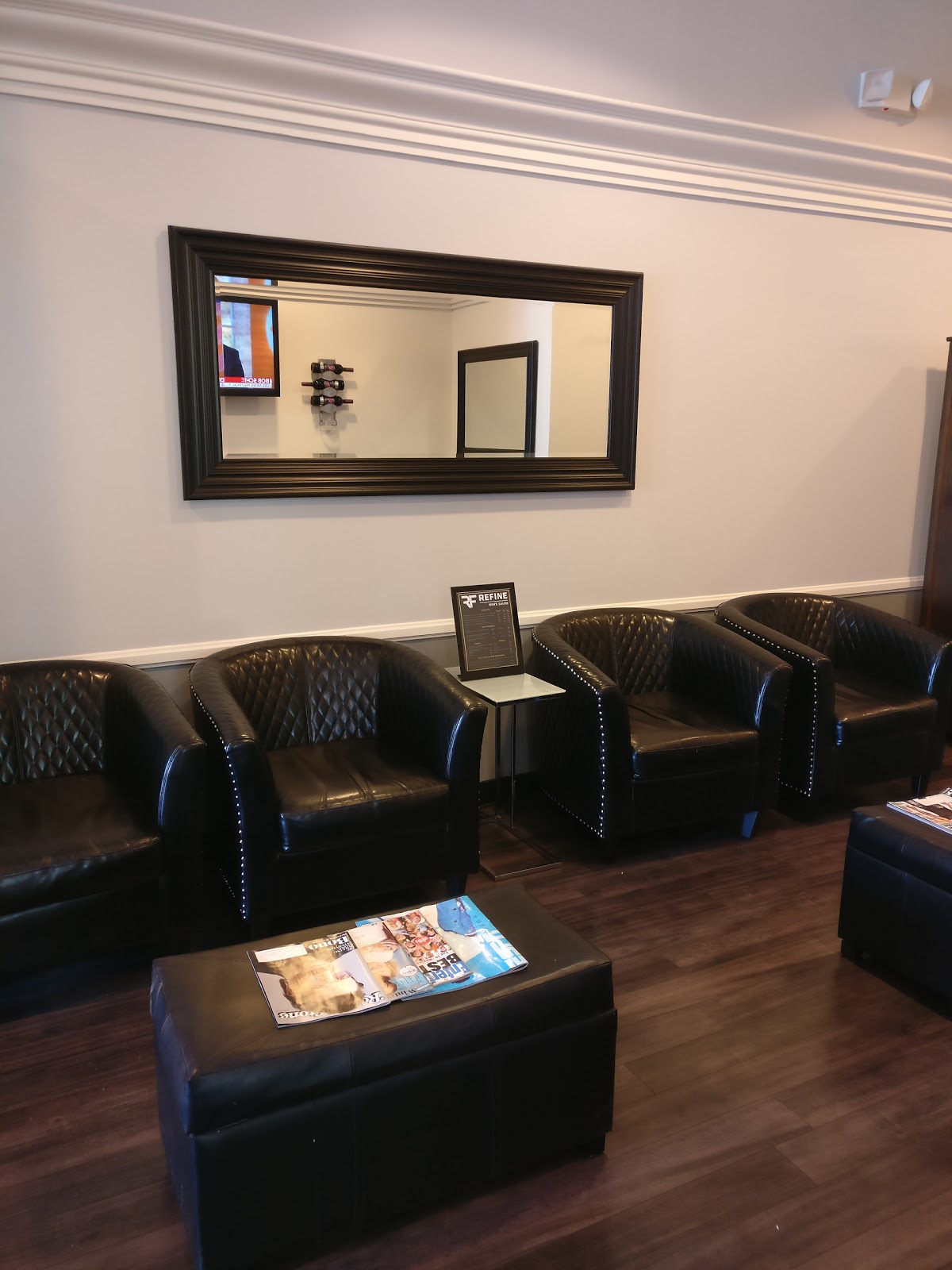 Black tufted leather club chairs in the Refine Men's Salon waiting lounge