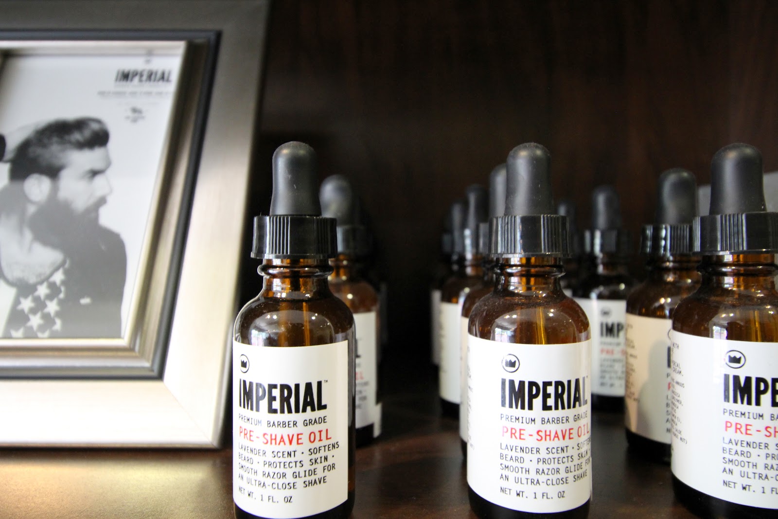 Imperial premium barber-grade pre-shave oil bottles on a dark wood shelf at Refine Men's Salon