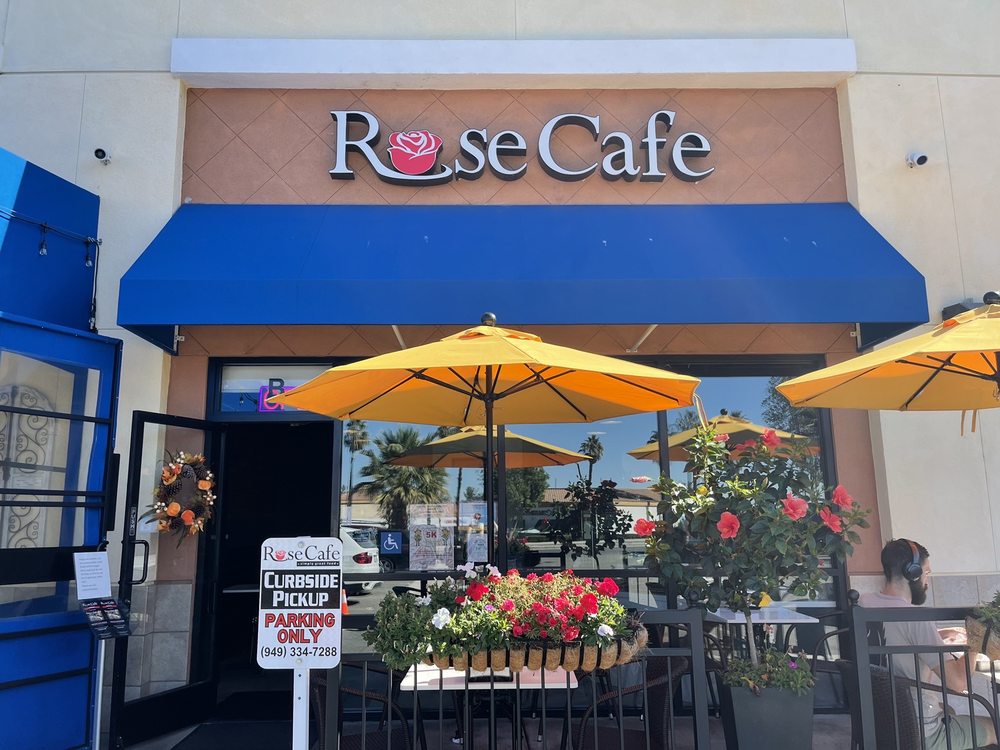 The Rose Cafe storefront with its rose sign, blue awning, and flower-lined patio in Lake Forest