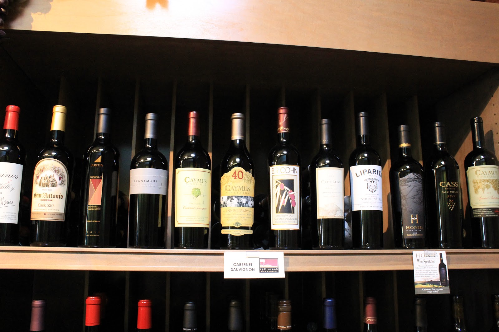 A shelf of Cabernet Sauvignon at Salt Creek Wine Company, Caymus and Honig among the labels, with the shop's own shelf tag