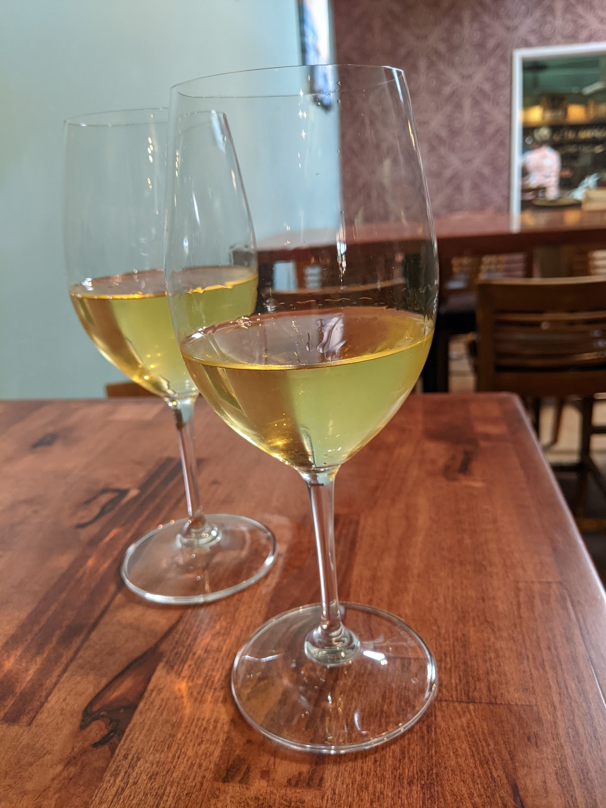 Two glasses of chilled white wine on a wood tasting table at Salt Creek Wine Company