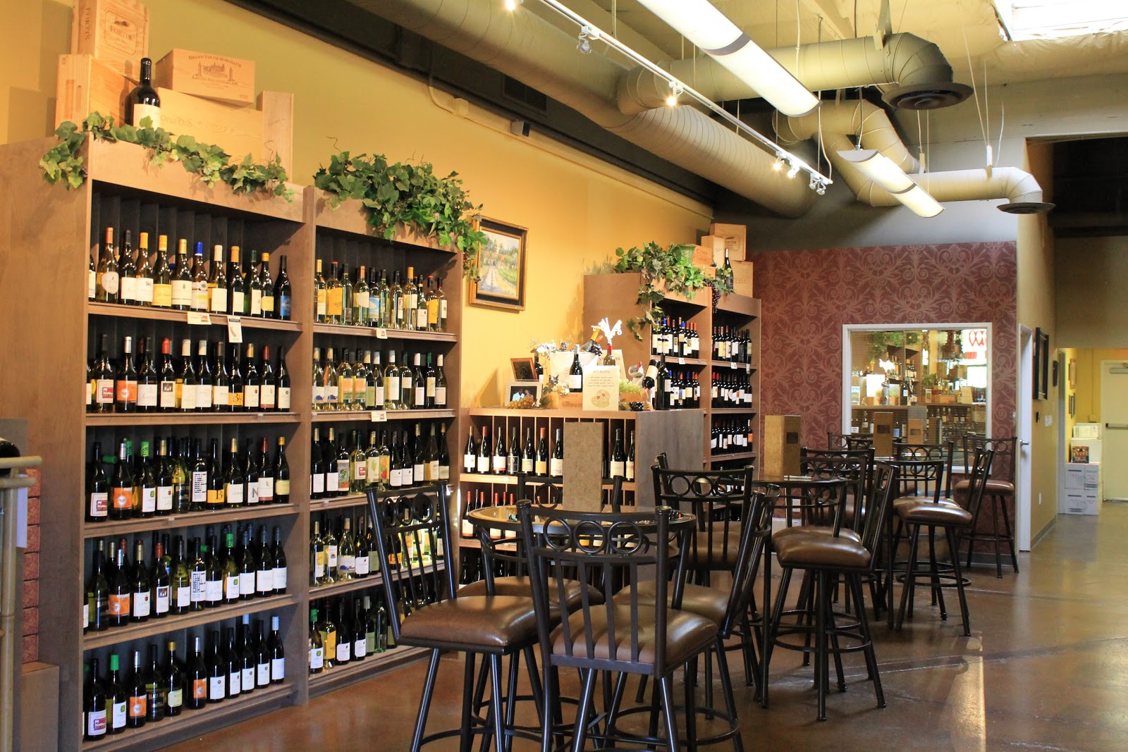 The interior of Salt Creek Wine Company, a wall of wine bottles beside high-top tables