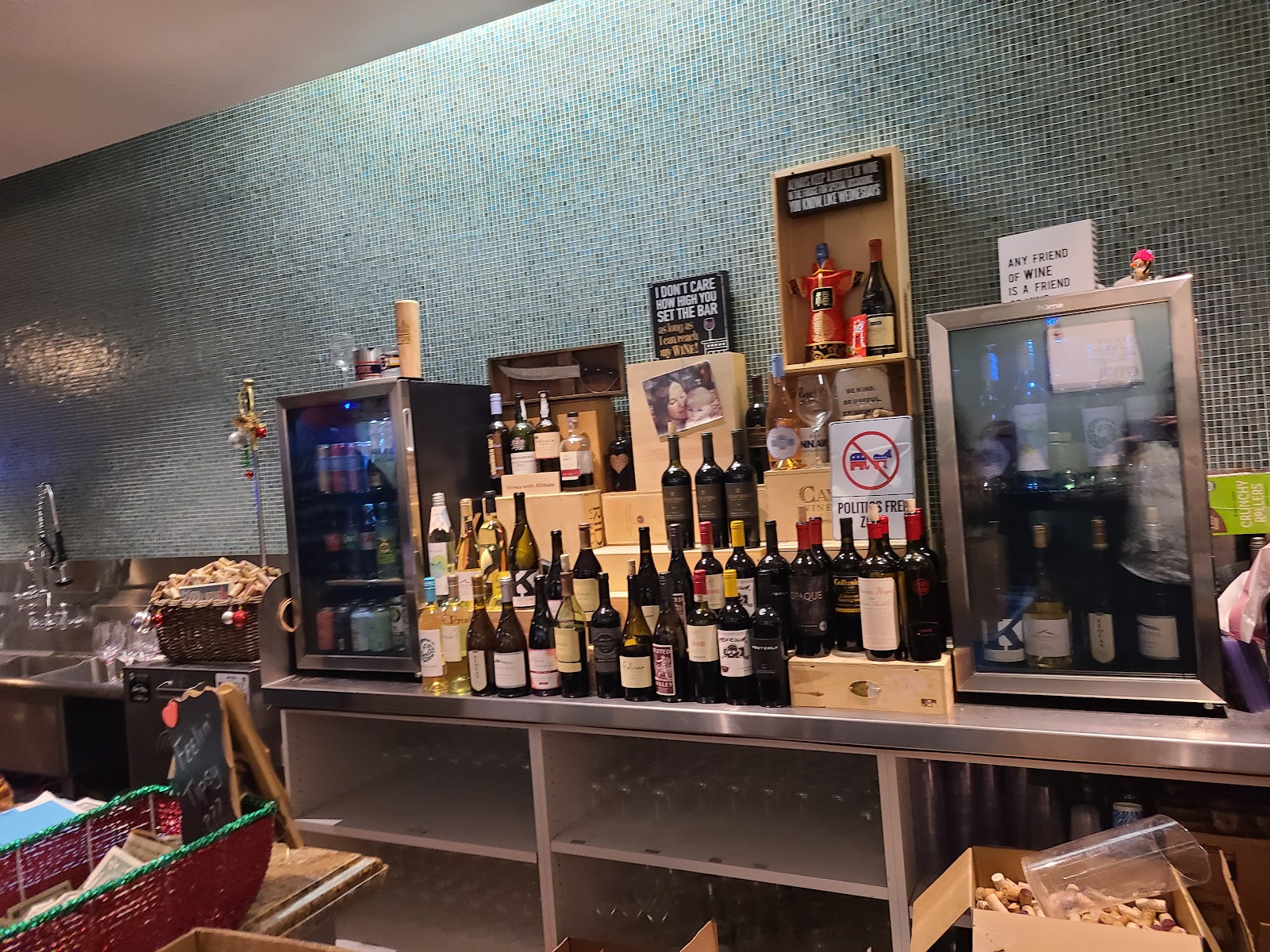 The bar at Salt Creek Wine Company with a teal glass-tile mosaic wall and a sign reading Any Friend of Wine is a Friend