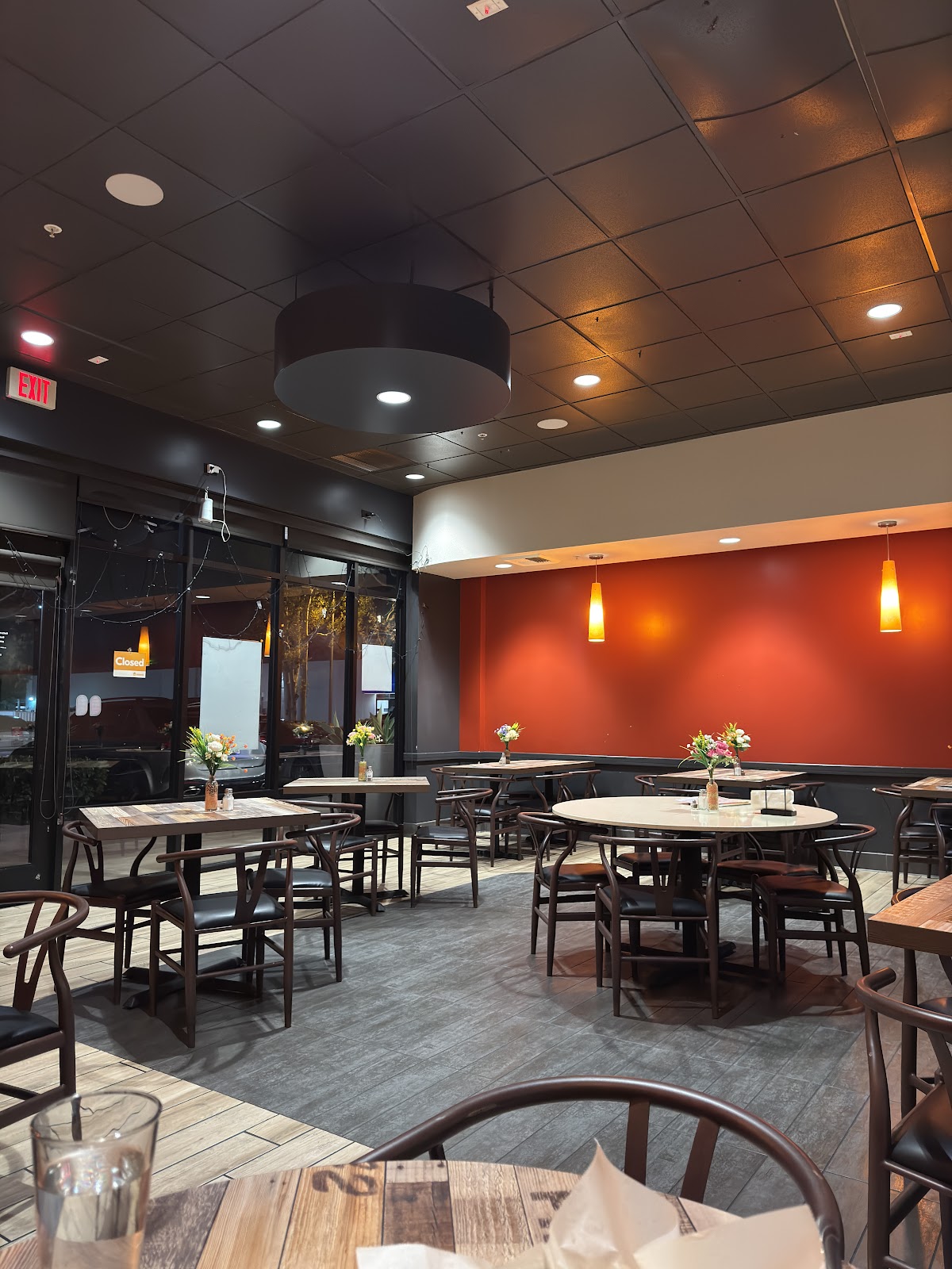 The Sattva Indian Rasoi dining room, with a warm terracotta accent wall, amber pendant lamps, wood tables, and fresh flowers