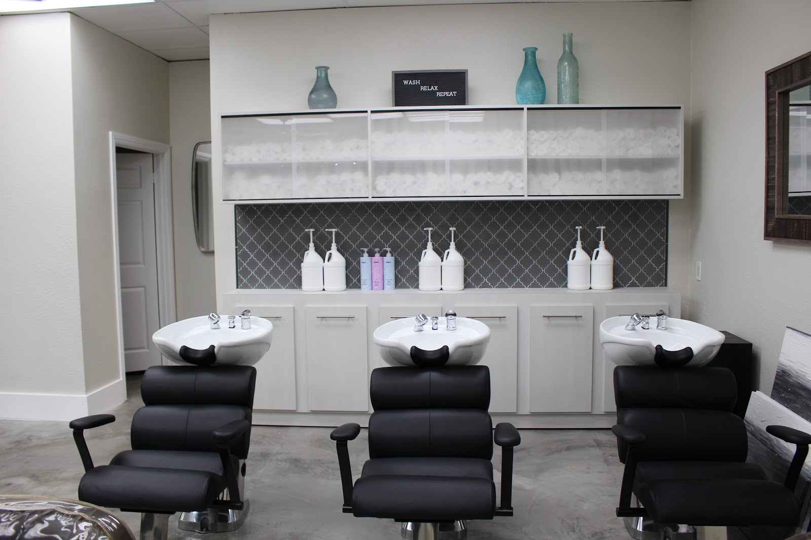 The wash stations at Secrets Salon, with a Wash Relax Repeat sign